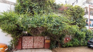 A gated entrance with a decorative metal gate, a paved pathway leading to the gate, and a parked car to the right. - Harpalsar Haveli Jaipur (Jaipur)
