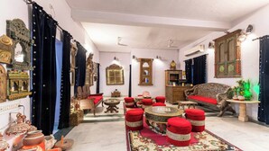 A traditional room with a sofa, ottomans, a patterned rug, and decorative items. - Harpalsar Haveli Jaipur (Jaipur)