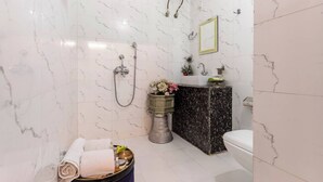 A bathroom with a marble shower, a toilet, and a sink with a decorative vase. - Harpalsar Haveli Jaipur (Jaipur)