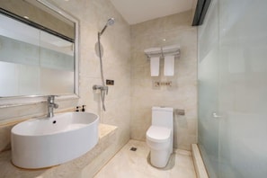 A modern bathroom with a round sink, a toilet, and a glass shower enclosure.