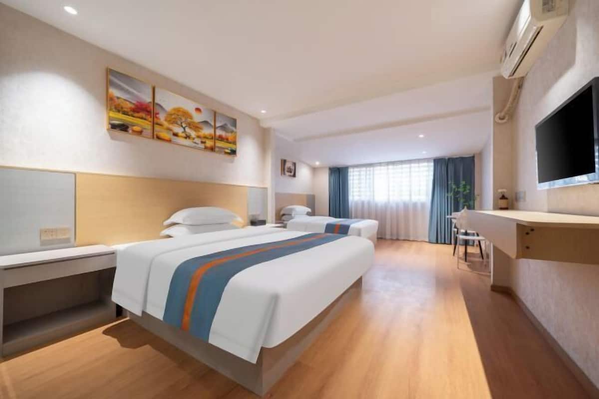 Una habitación de hotel con una cama grande, un escritorio, un televisor y un cuadro en la pared.
