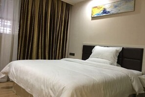 Una habitación de hotel con una cama grande, cabecera, mesita de noche y un cuadro en la pared.