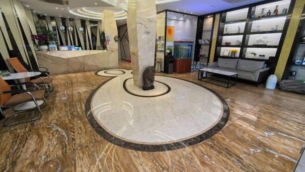 Un vestíbulo con piso de mármol, una recepción, zona de estar y una exhibición de objetos decorativos.