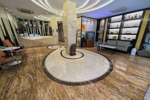 A lobby with a marble floor, seating area, reception desk, and a wall with shelves.