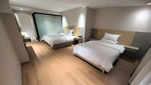 Una habitación de hotel moderna con dos camas, un ventanal grande y suelo de madera.