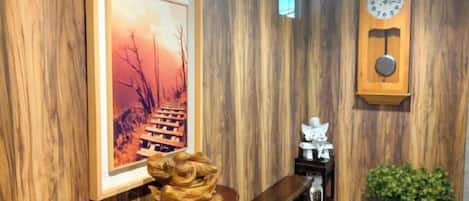 Una pared de madera con un cuadro enmarcado, un reloj de madera y un pequeño banco.