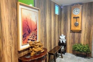 Una pared de madera con un cuadro enmarcado, un reloj de madera y un pequeño banco.