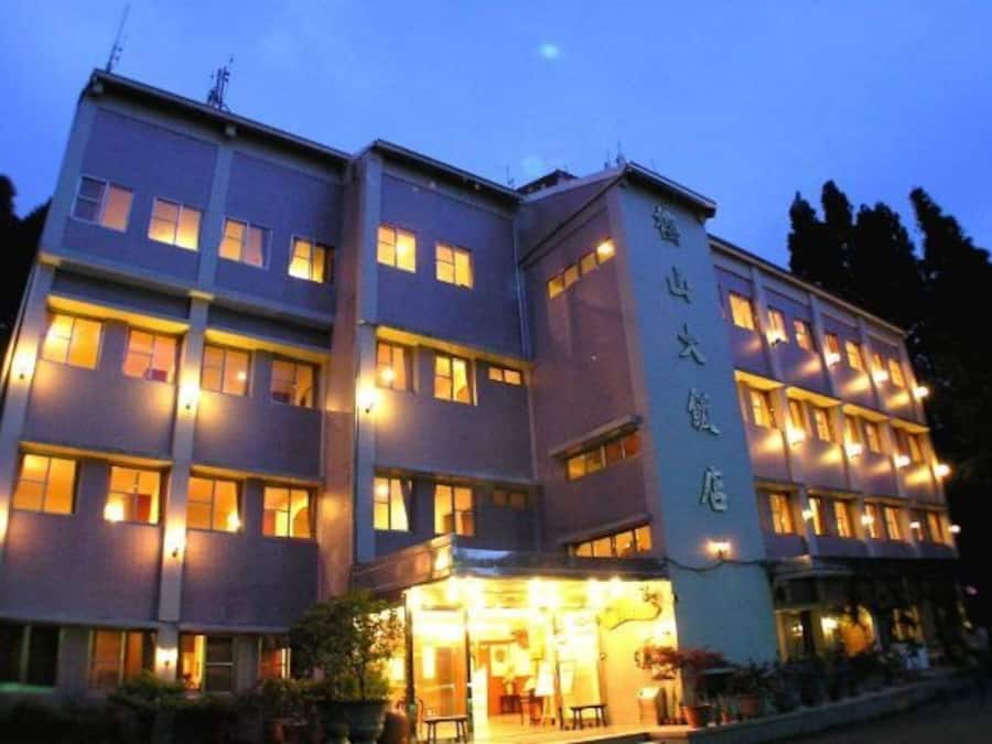 A multi-story hotel with illuminated windows and a well-lit entrance.