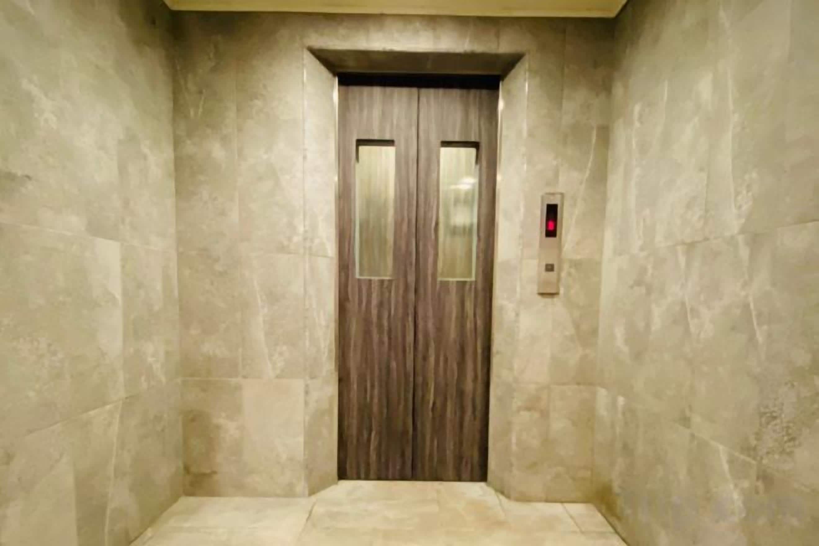 An elevator with a wooden door and a red emergency light.