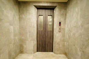 Een lift met een houten deur en een rood noodlicht.
