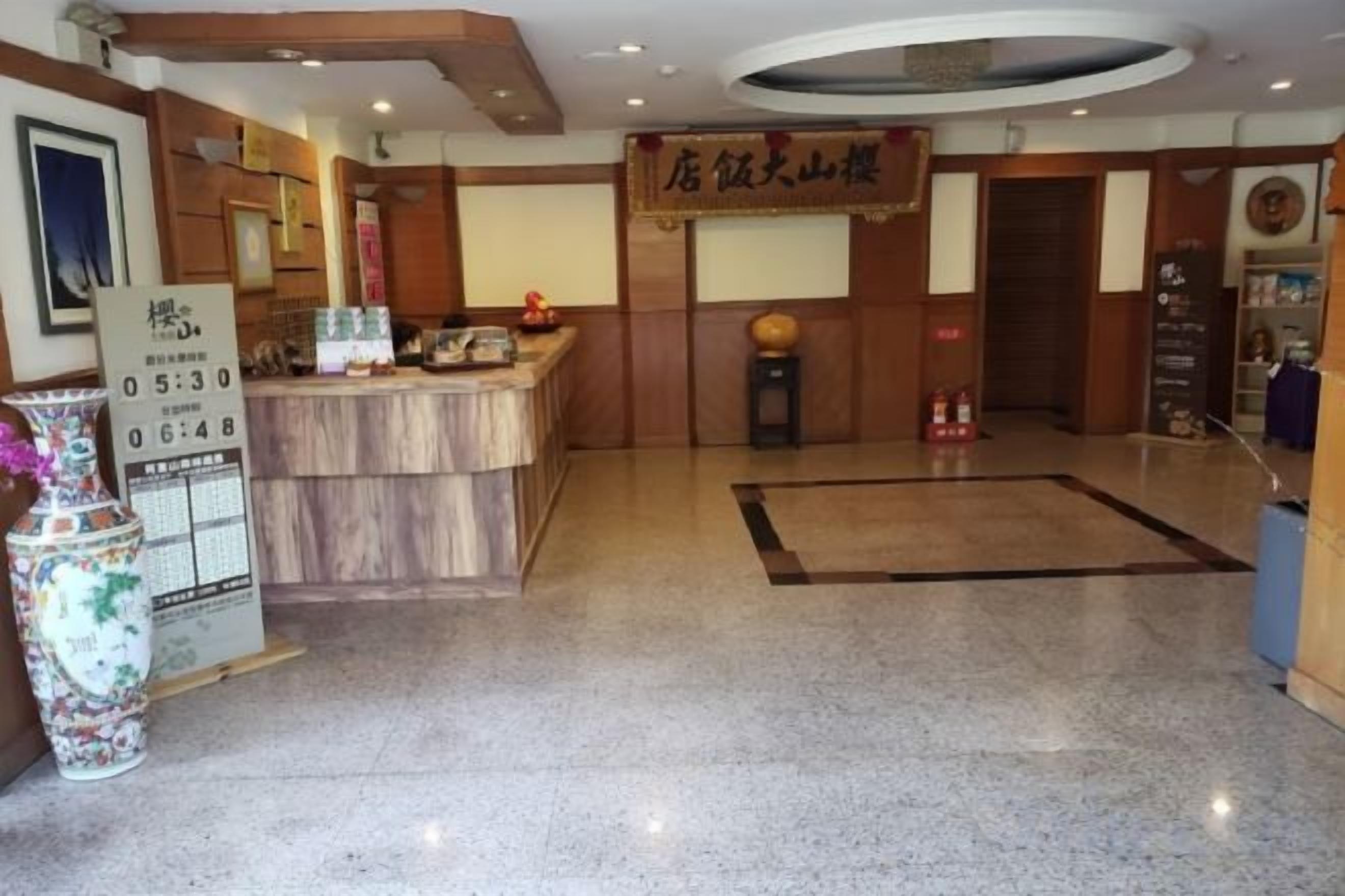 A hotel reception area with a reception desk, a clock, and a sign above the desk.