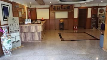 A hotel reception area with a reception desk, a clock, and a sign above the desk.