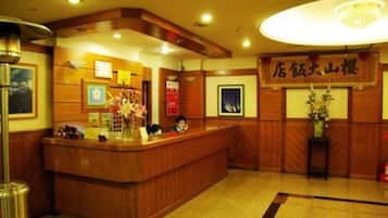 A reception desk with a wooden finish, a chandelier above, and a sign with Japanese characters.