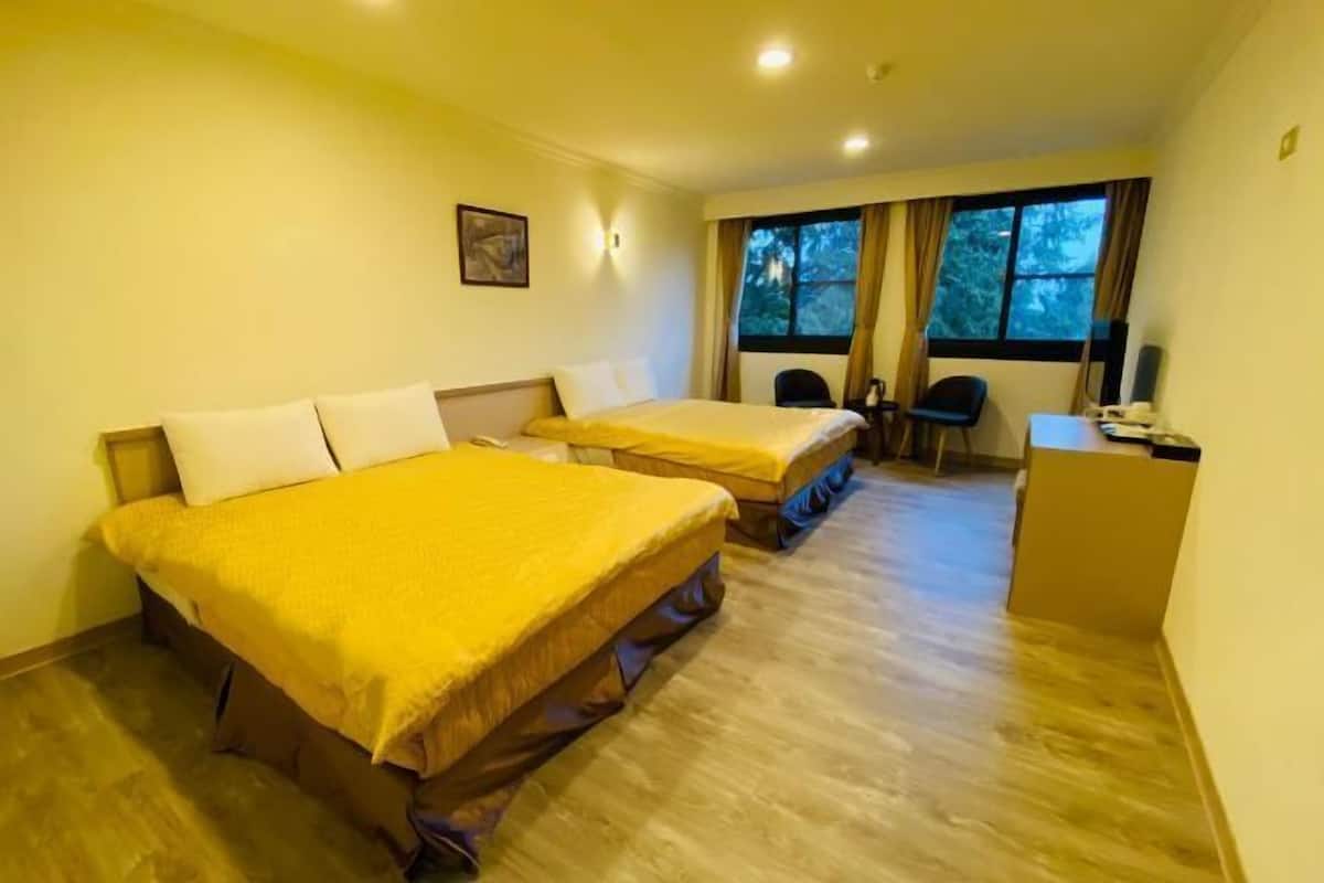 A hotel room with two beds, a desk, and a window with curtains.