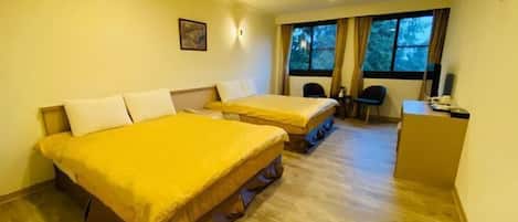 A hotel room with two beds, a desk, and a window with curtains.