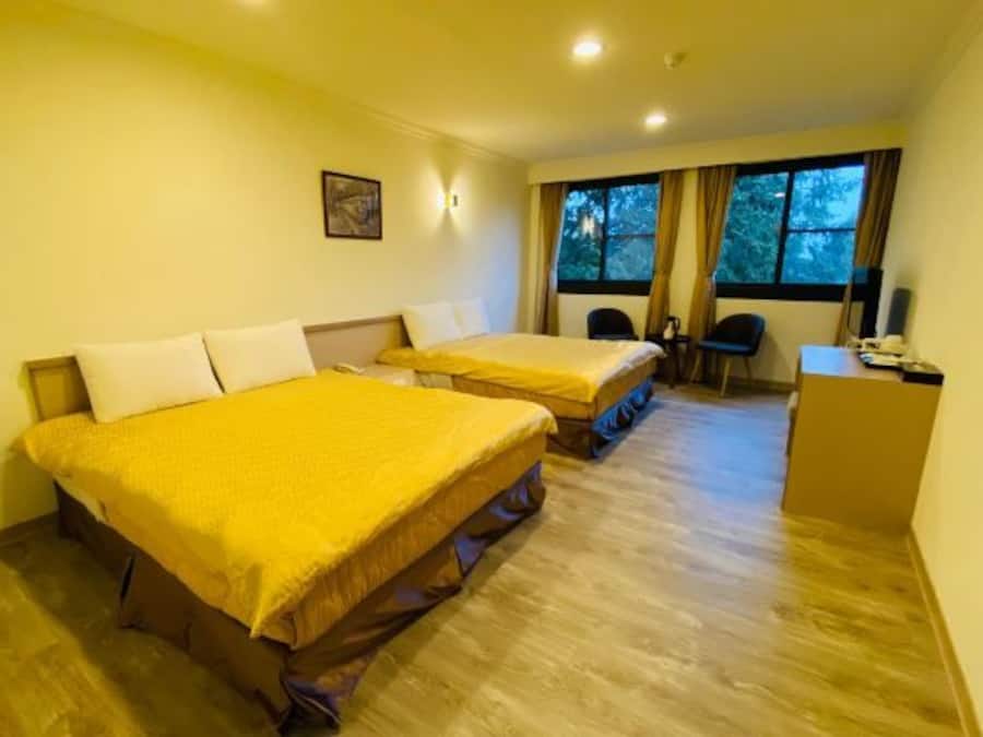A hotel room with two beds, a desk, and a window with curtains.