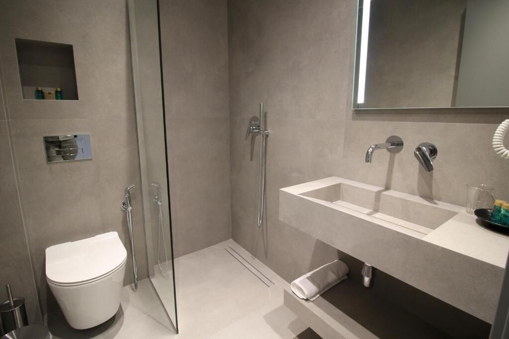 A modern bathroom with a glass shower enclosure, a white toilet, and a vanity with a mirror.