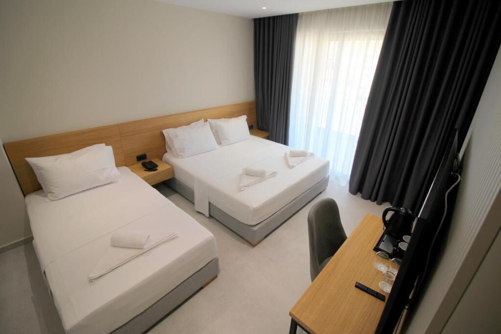 A hotel room with two beds, a desk, and a chair.