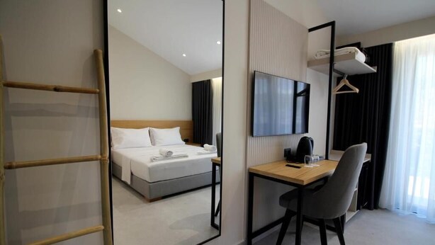 A hotel room with a bed, a desk, a chair, a TV, and a wardrobe. - Niklas Boutique Hotel (Sarandë)