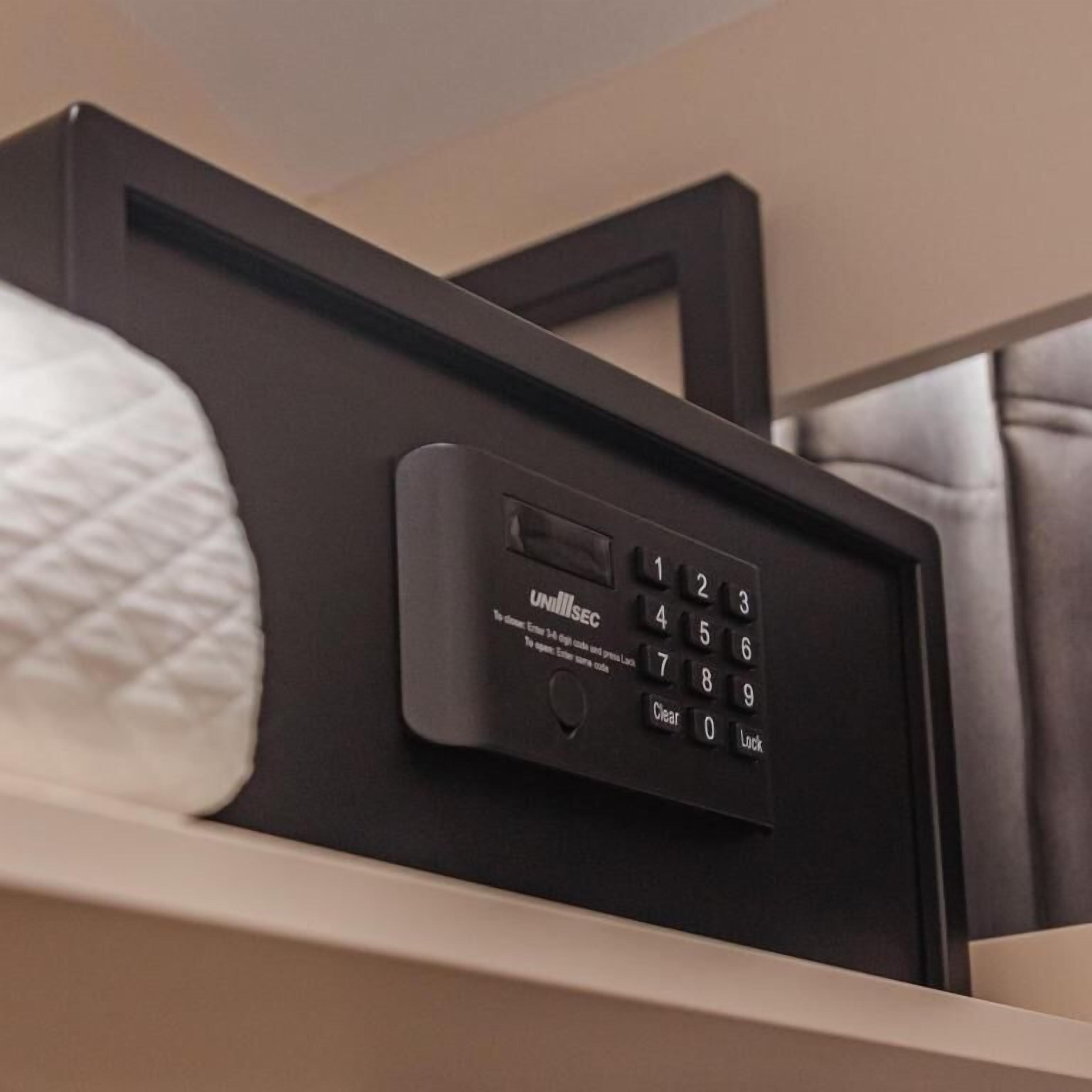 A black electronic device with a keypad and a small screen, likely a control panel for room amenities.