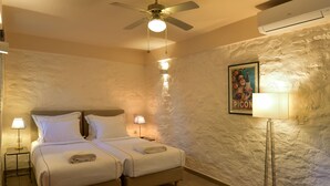 Ein Zimmer mit zwei Betten, einem Deckenventilator, einer Klimaanlage und einem Poster an der Wand.
