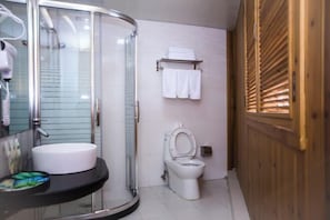 A bathroom with a glass-enclosed shower, a white sink, and a toilet.