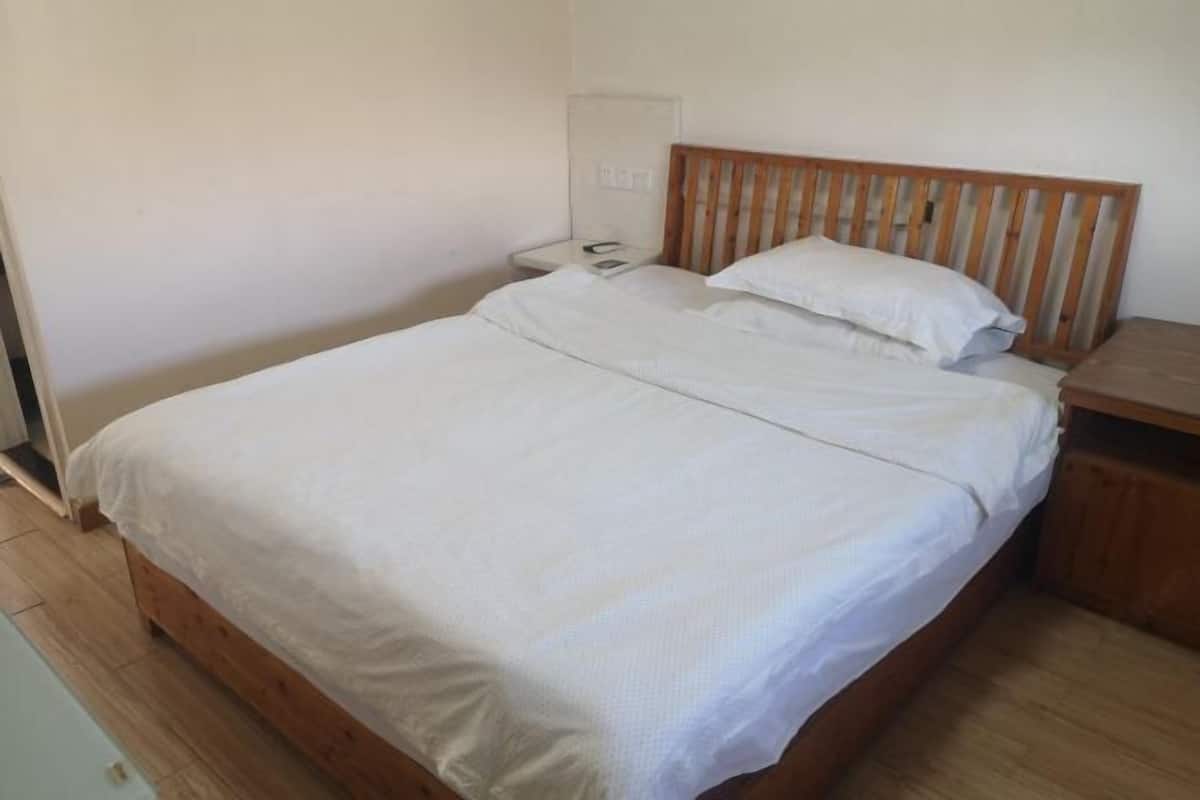 A single bed with a wooden headboard, a bedside table, and a nightstand.