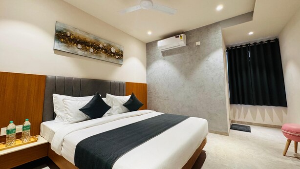 A neatly arranged hotel room with a bed, bedside table, and a ceiling fan. - Hotel Rudhav Palace (Ujjain)