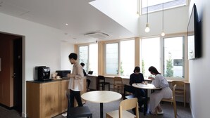 A modern office space with a coffee station, round tables, and large windows. - Kamishihoro Hotel (Kamishihoro)