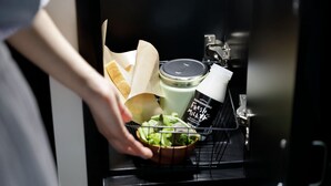A hand reaching into a kitchen cabinet, pulling out a bowl of salad, a jar of milk, and a container of fresh milk. - Kamishihoro Hotel (Kamishihoro)