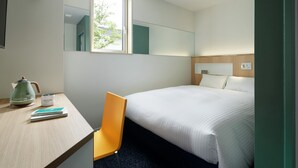 A hotel room with a bed, a desk with a chair, a kettle, and a mug. - Kamishihoro Hotel (Kamishihoro)