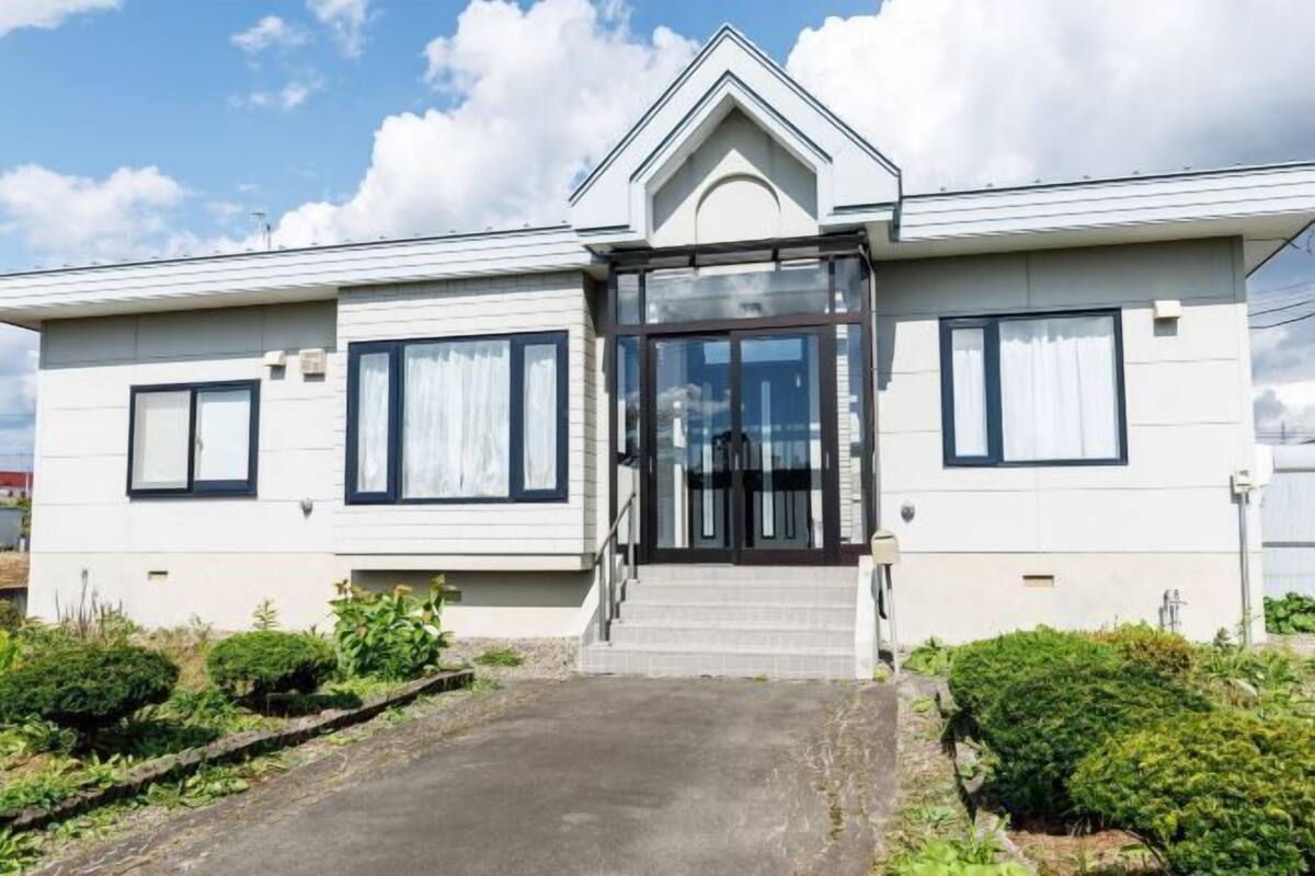 Une maison moderne à deux étages, dotée d’une entrée à l’avant, d’un petit porche et d’une allée menant à l’entrée.