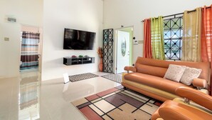 A modern living room with a flat-screen TV, leather sofa, and a patterned rug. - 5 Bedroom Haven in Draxhall (Ocho Rios)