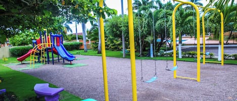 A playground with swings, a slide, and a picnic table.