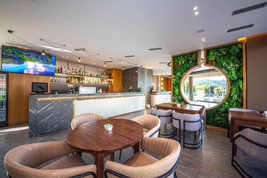 Un'area bar moderna con bancone in marmo, posti a sedere comodi e un grande schermo televisivo.