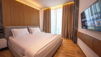Une chambre d’hôtel moderne dotée d’un grand lit, de murs recouverts de panneaux de bois, d’un téléviseur à écran plat et d’une grande fenêtre avec des rideaux.