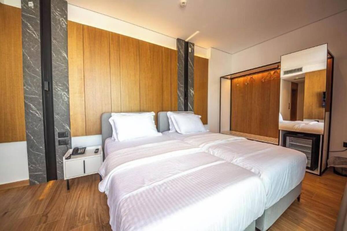 Una habitación de hotel moderna con una cama grande, paredes de paneles de madera y una pared de acento de mármol.