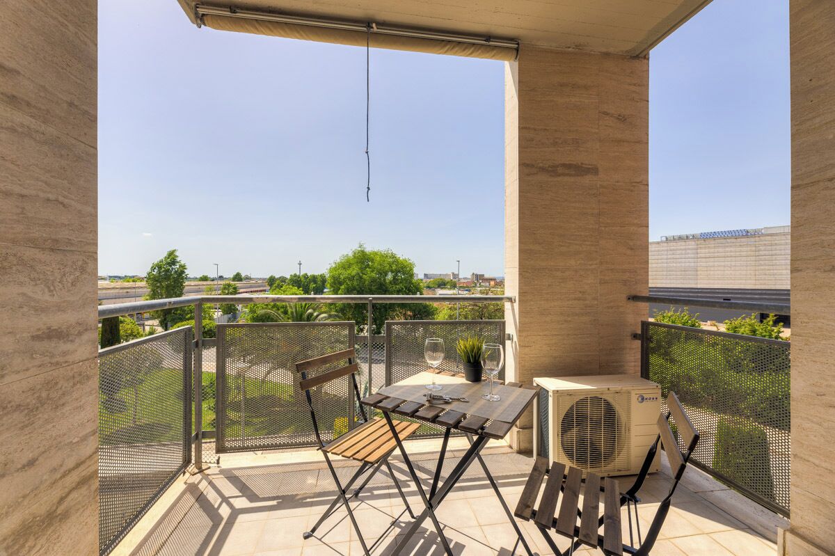 A balcony with a table, chairs, and an air conditioning unit.