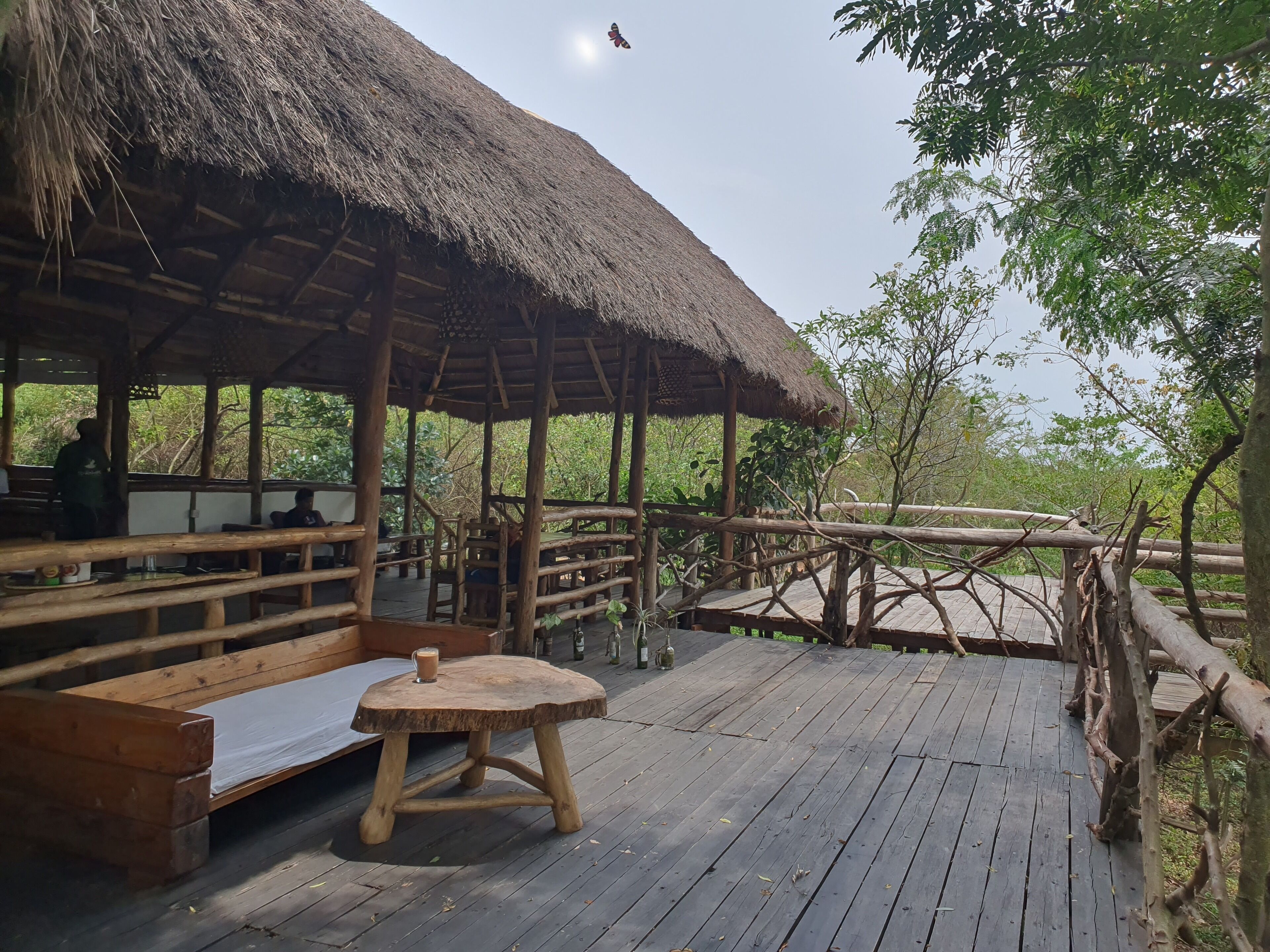 A wooden deck with benches and a table, surrounded by a wooden fence and trees.