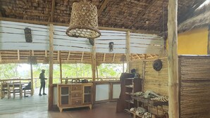 A rustic wooden interior with a thatched roof, wooden furniture, and a display of animal skulls. - Topi Lodge (Kihihi)
