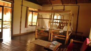 A room with a wooden four-poster bed, a woven mat on the floor, and a rustic ceiling. - Topi Lodge (Kihihi)