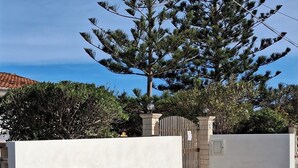 A gated driveway with a white wall and a metal gate, leading to a building with a tiled roof. - Villino Oleandro ad 1 Minuto a Piedi Dalla Spiaggia, Climatizzato e con Wifi (Santa Maria del Focallo)
