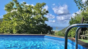 A swimming pool with clear blue water, surrounded by lush greenery and a view of the ocean. - Beautiful private villa for 13 guests with private pool, A/C, TV and panoramic view (Capo D'orlando)