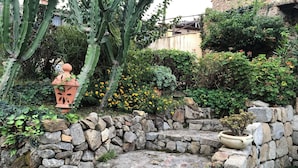 A stone garden with a cactus, yellow flowers, and a small wooden bridge. - Beautiful private villa for 13 guests with private pool, A/C, TV and panoramic view (Capo D'orlando)