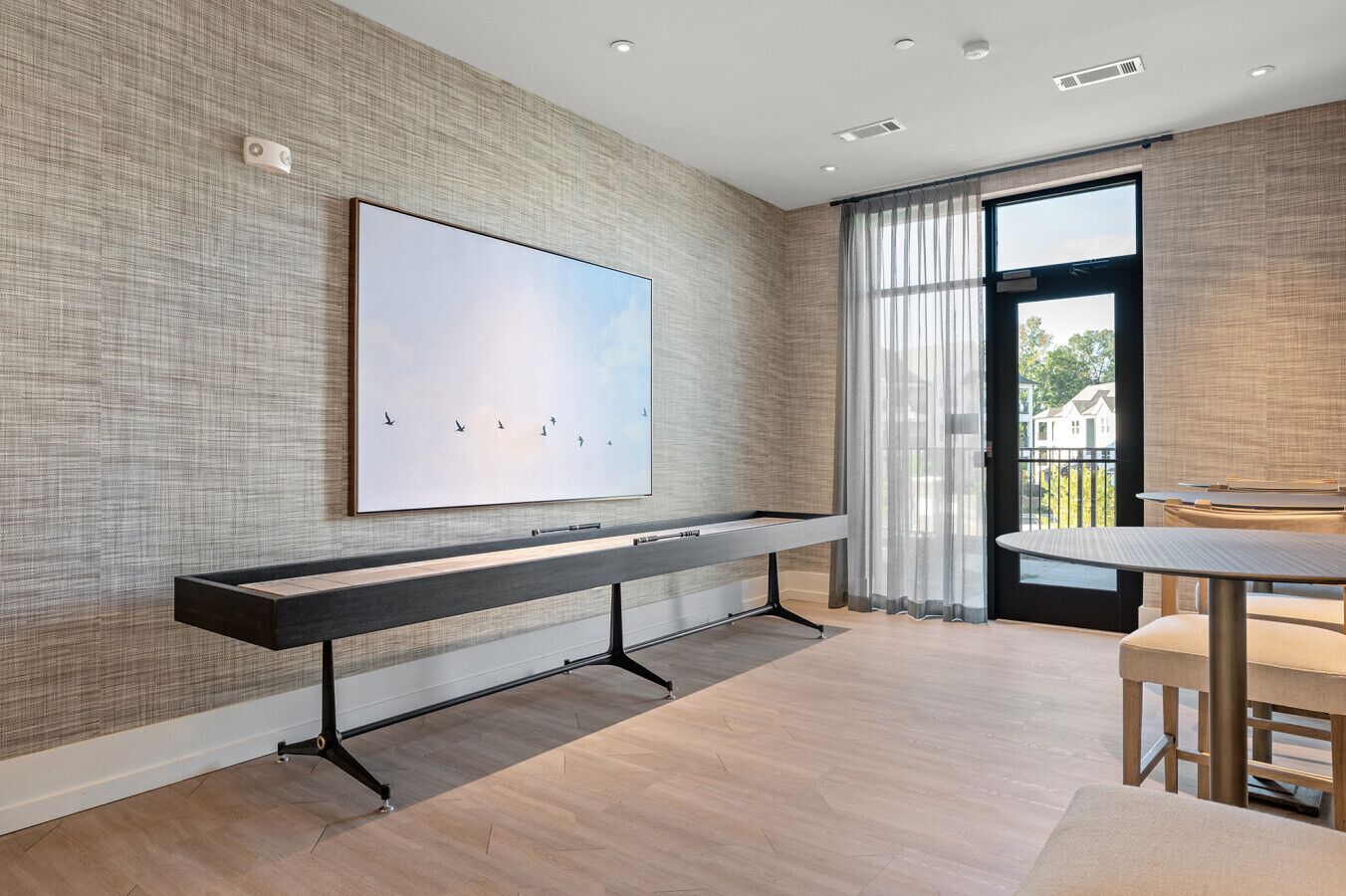 Een moderne kamer met een lange bank, een groot kunstwerk in een lijst en uitzicht door een glazen deur.