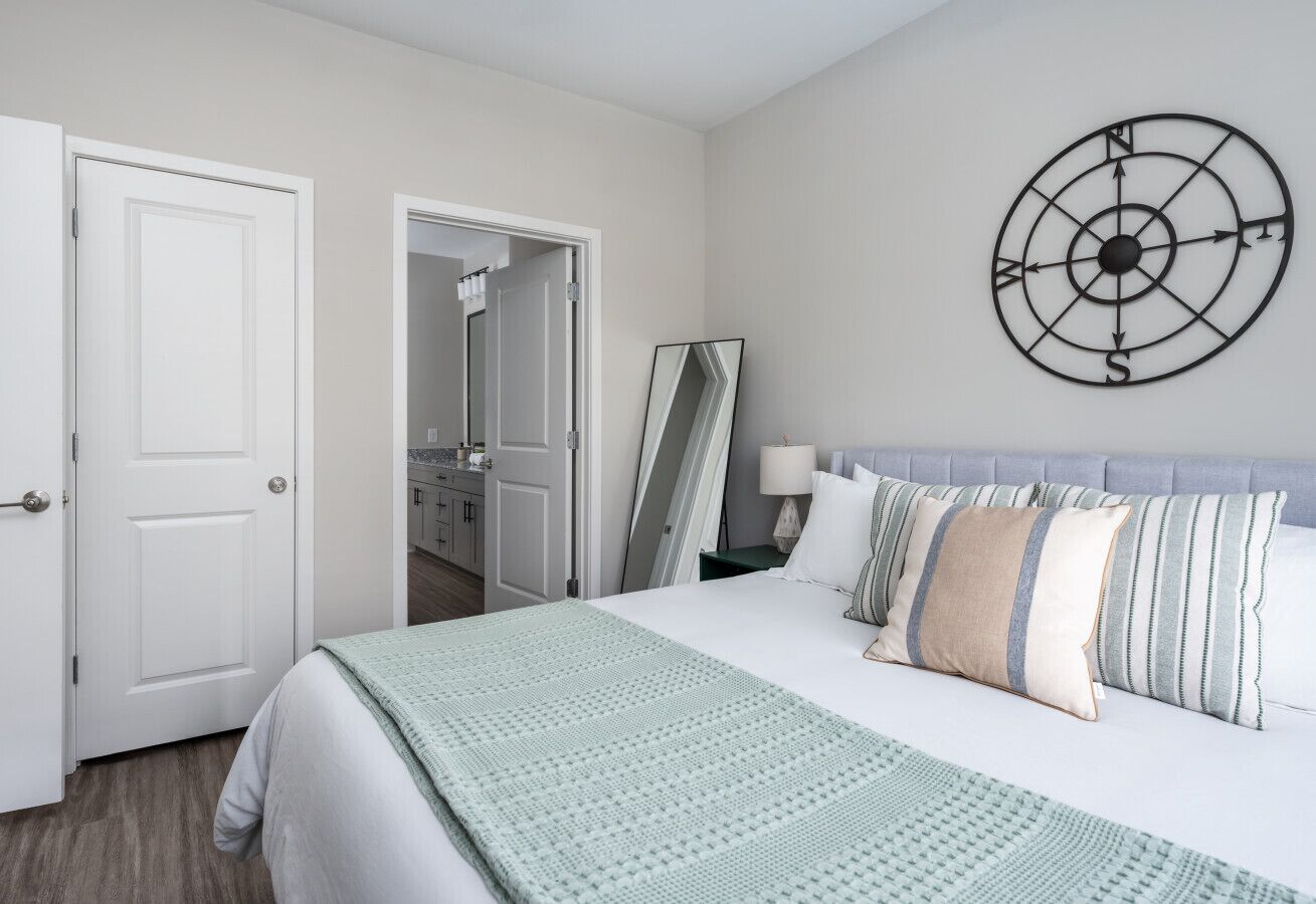 A bedroom with a bed, a wall clock, and a door leading to a bathroom.