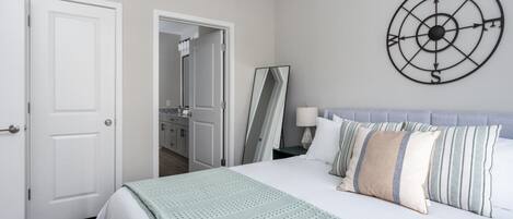 A bedroom with a bed, a wall clock, and a door leading to a bathroom.