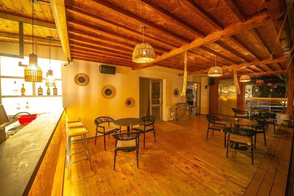 A cozy restaurant with wooden floors, a bar area, and hanging pendant lights.
