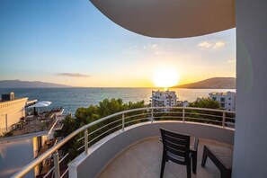 A balcony with a view of the sea and mountains at sunset.
