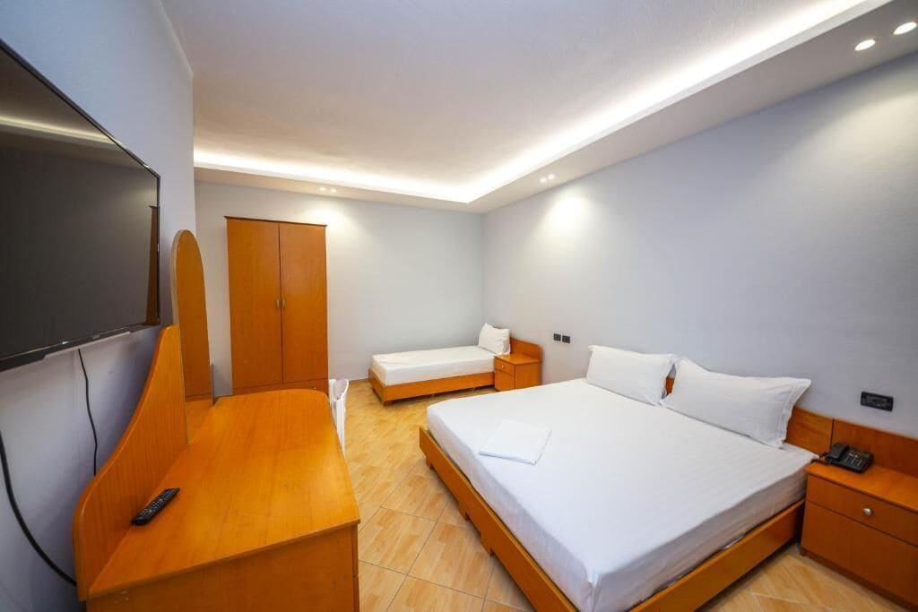 A hotel room with a bed, a desk, a television, and a wardrobe.
